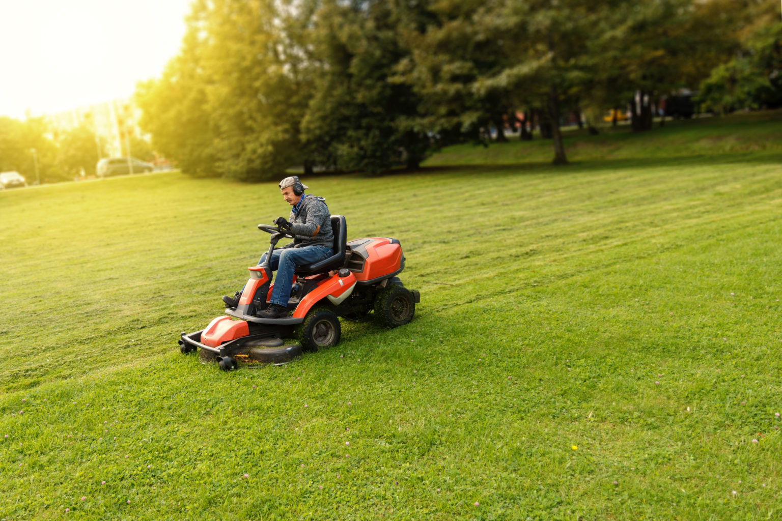 Men riding a lawnmower in a sunny day